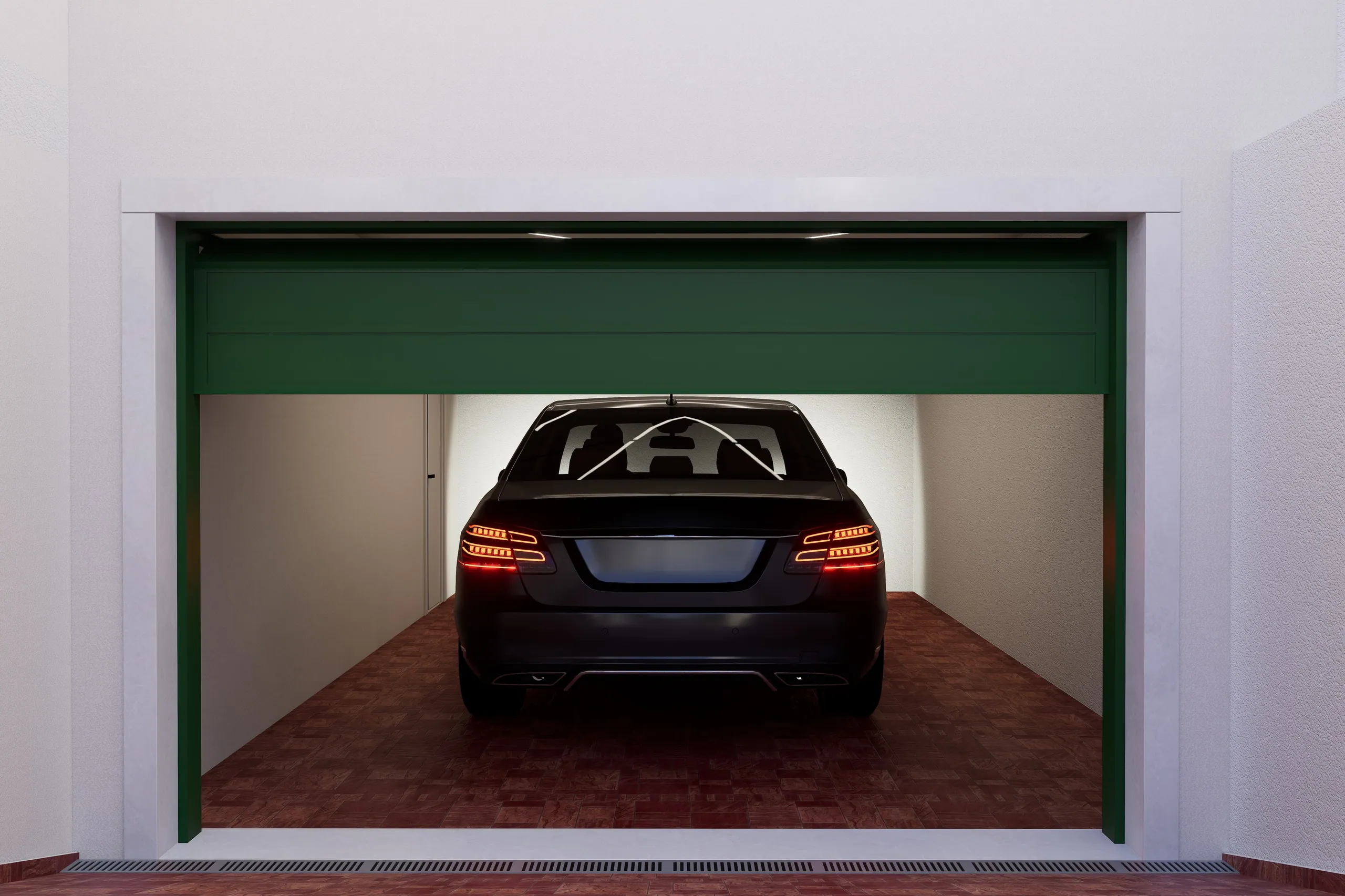 Garagem da cave com portão verde aberto e um automóvel estacionado.