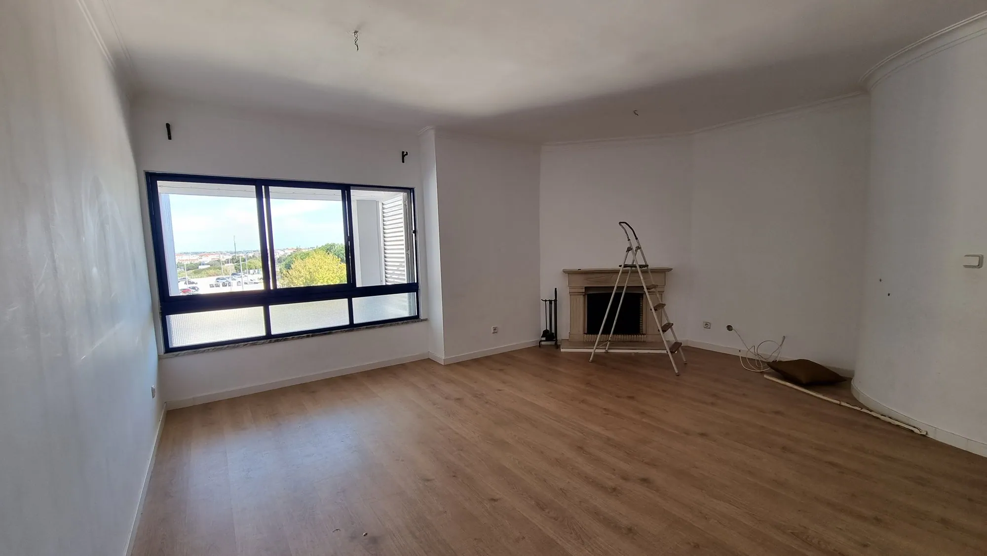 Antes da obra: a sala vazia, com a lareira antiga ao fundo.