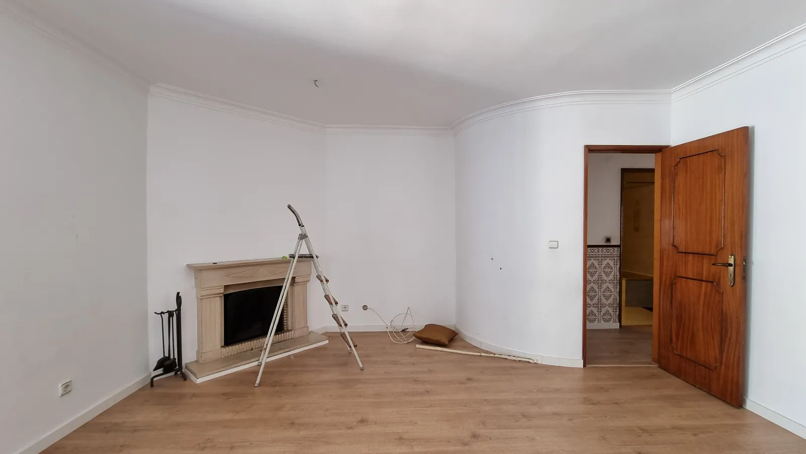 A sala antes da obra, vazia, com lareira de canto.