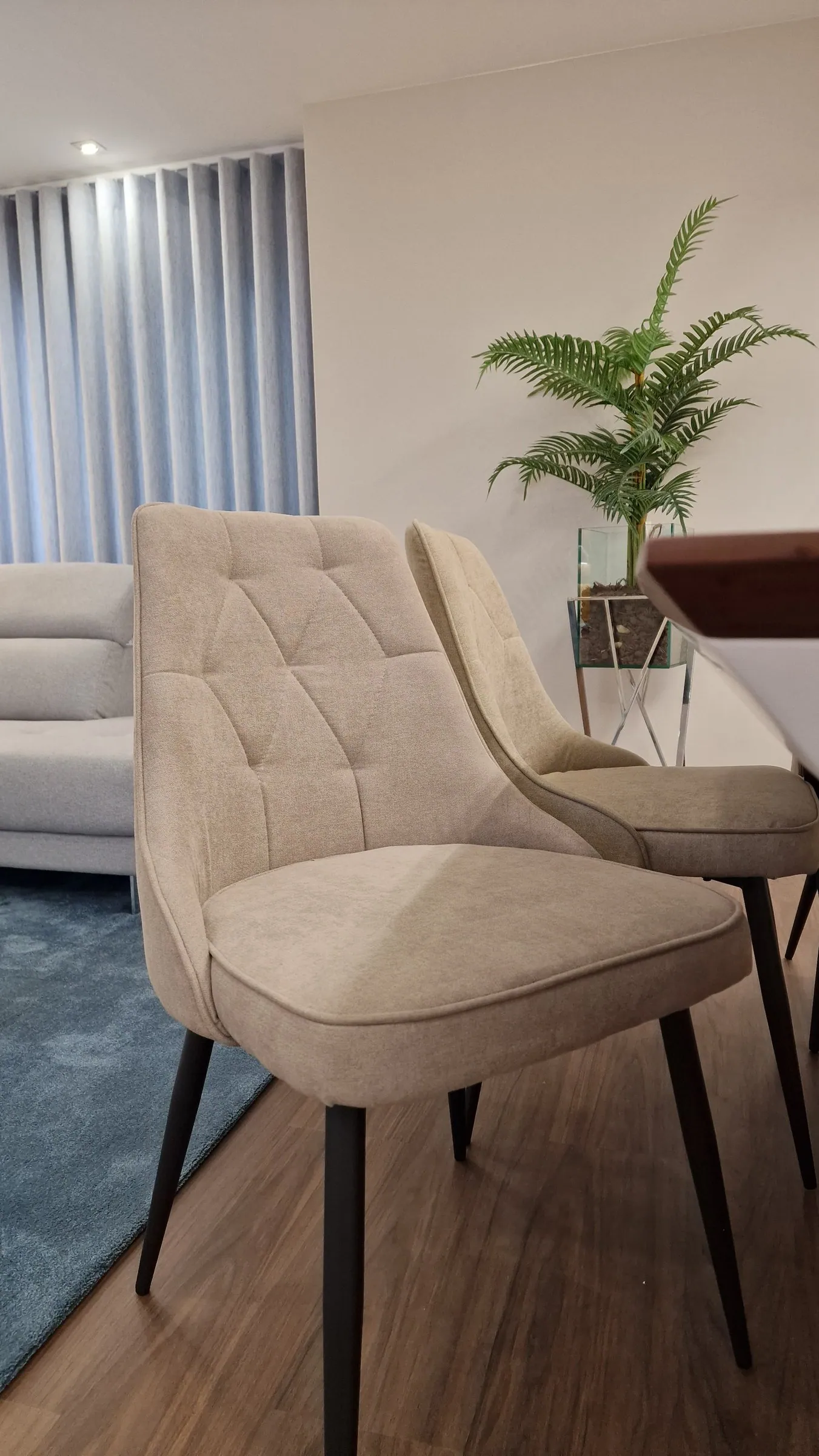 Uma cadeira estofada em tecido claro, junto à mesa de jantar.