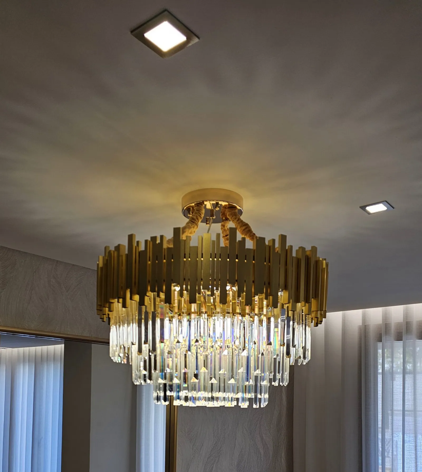 Candeeiro de teto em cristal e dourado sobre a mesa de jantar.