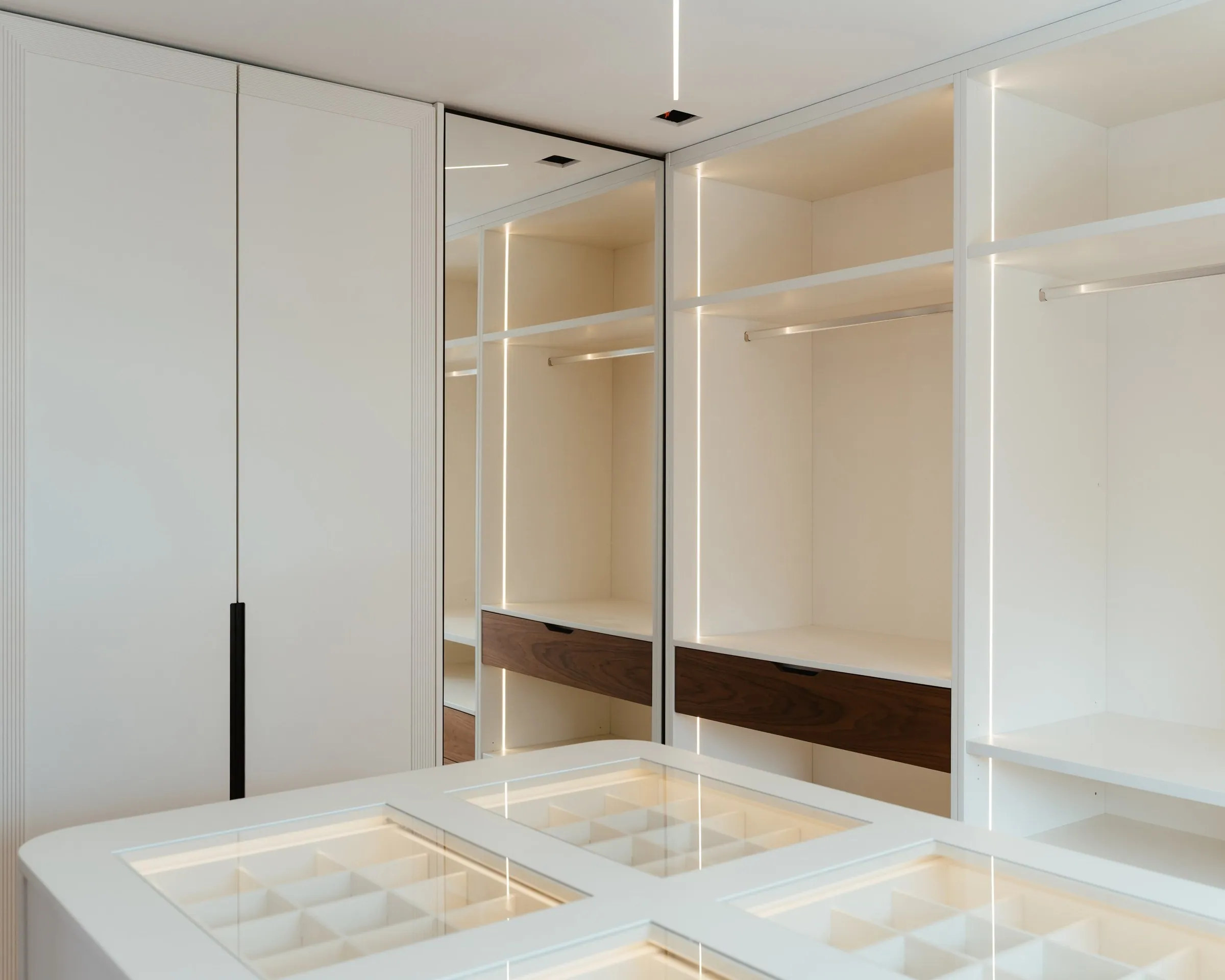 Closet com a ilha de tampo de vidro e os roupeiros abertos.