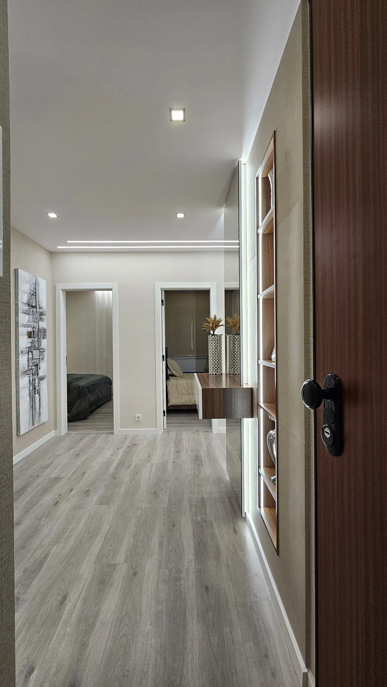 Corredor com porta em madeira escura e luz no teto.