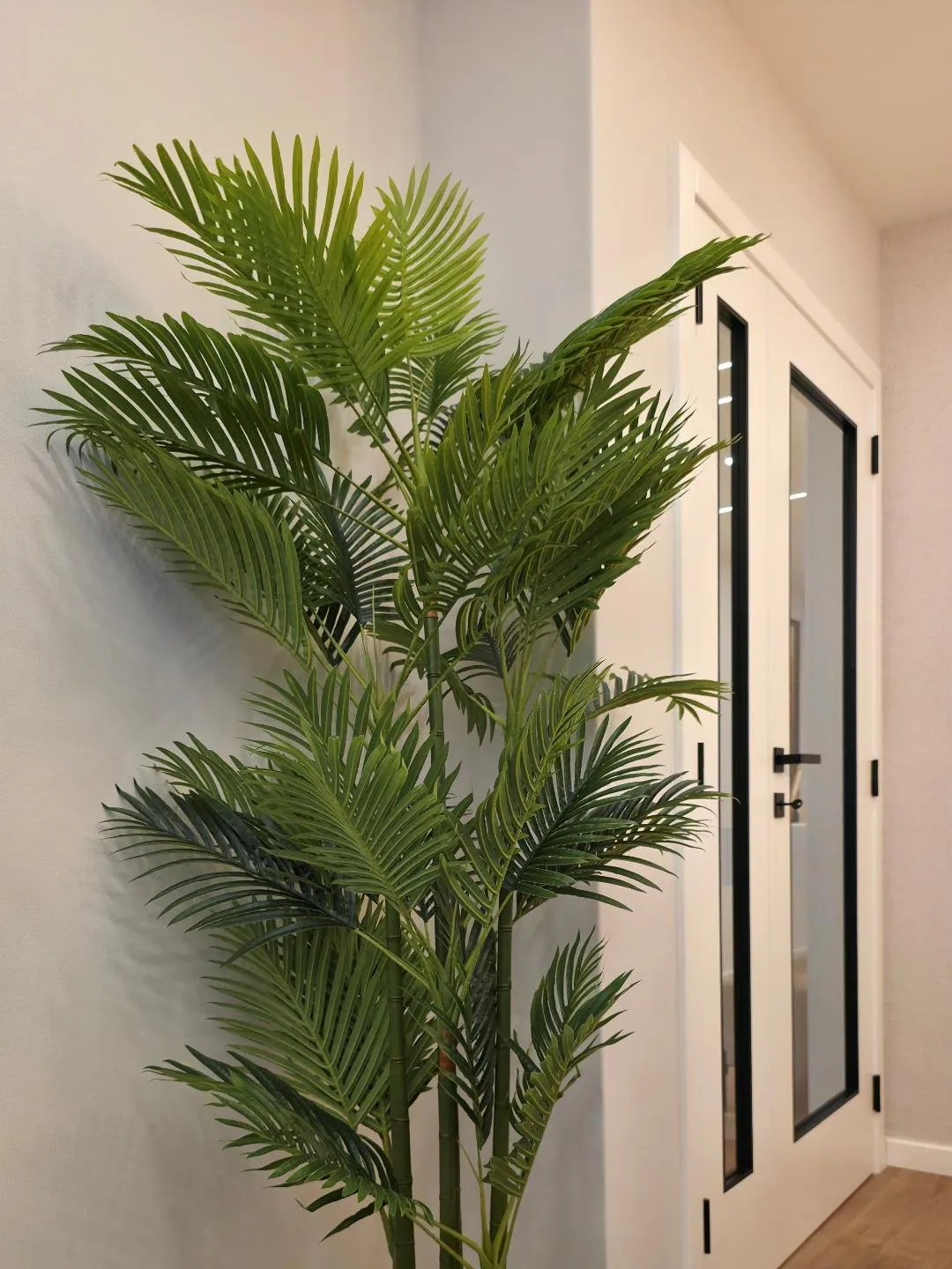 Planta em vaso dourado junto a uma porta branca.
