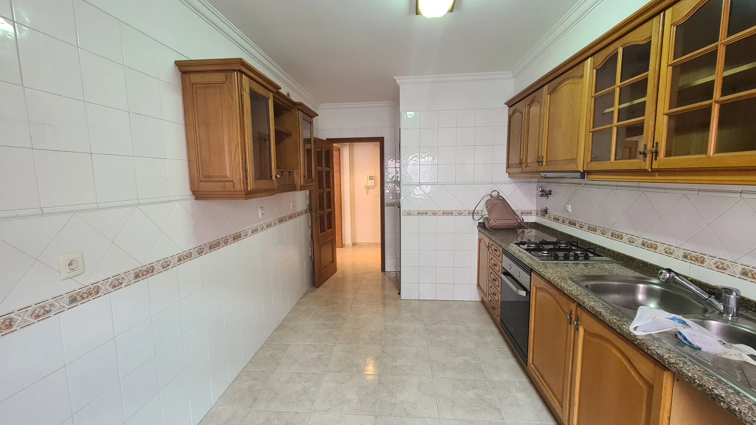 A cozinha antiga, de corredor, com armários de madeira.