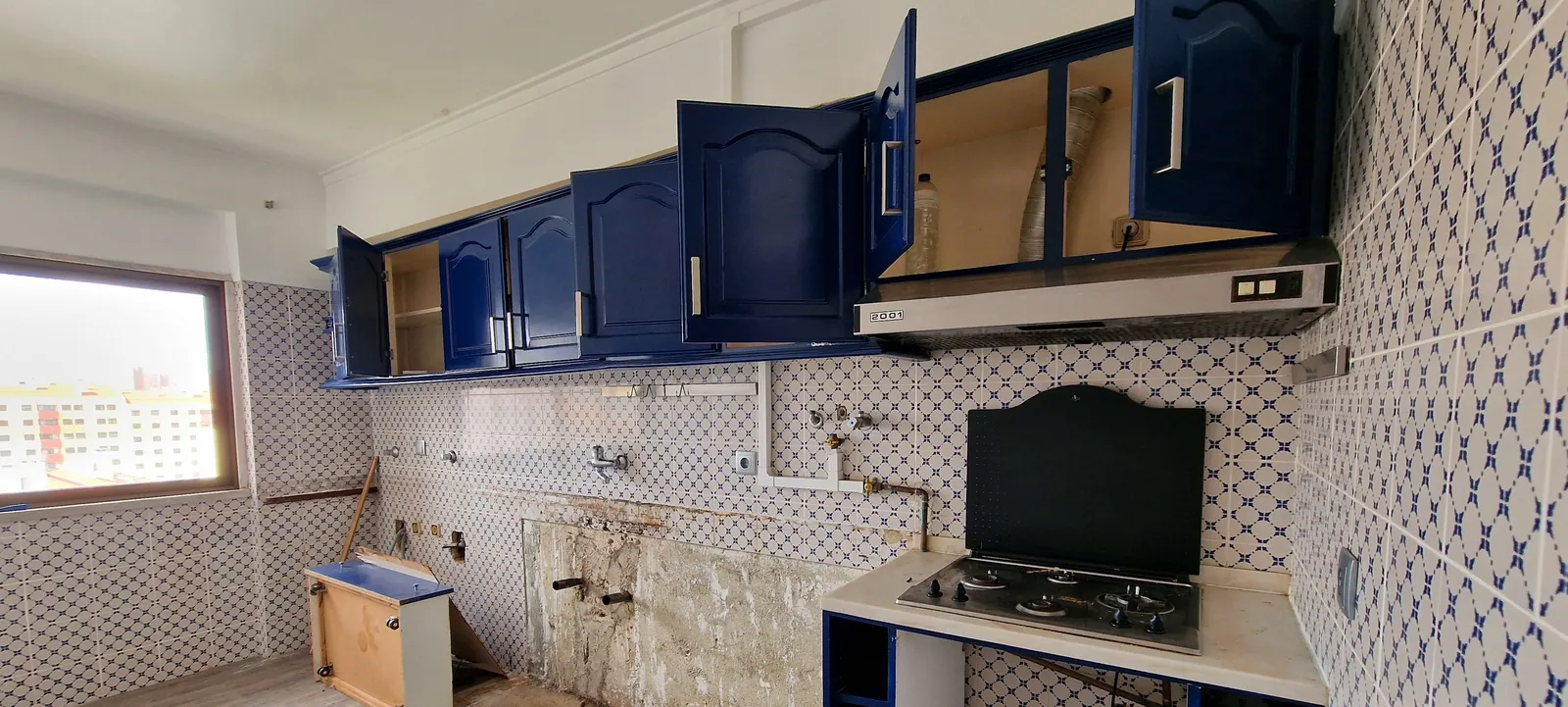 A cozinha antiga, com armários azuis e azulejo, antes da obra.