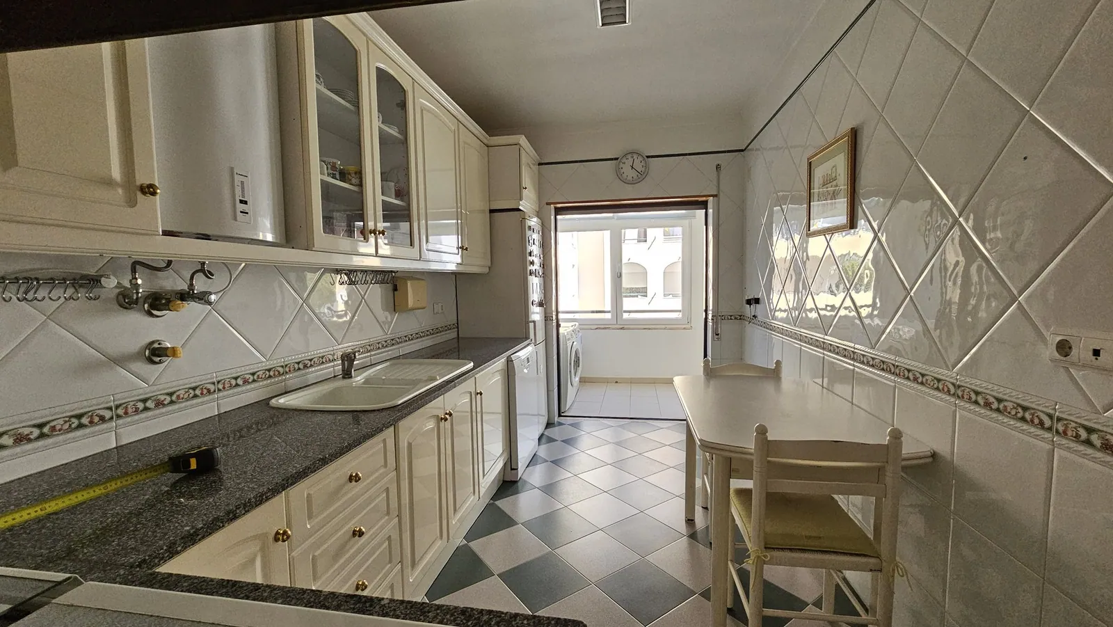 A bancada antes, com armários de frente creme e azulejo branco.
