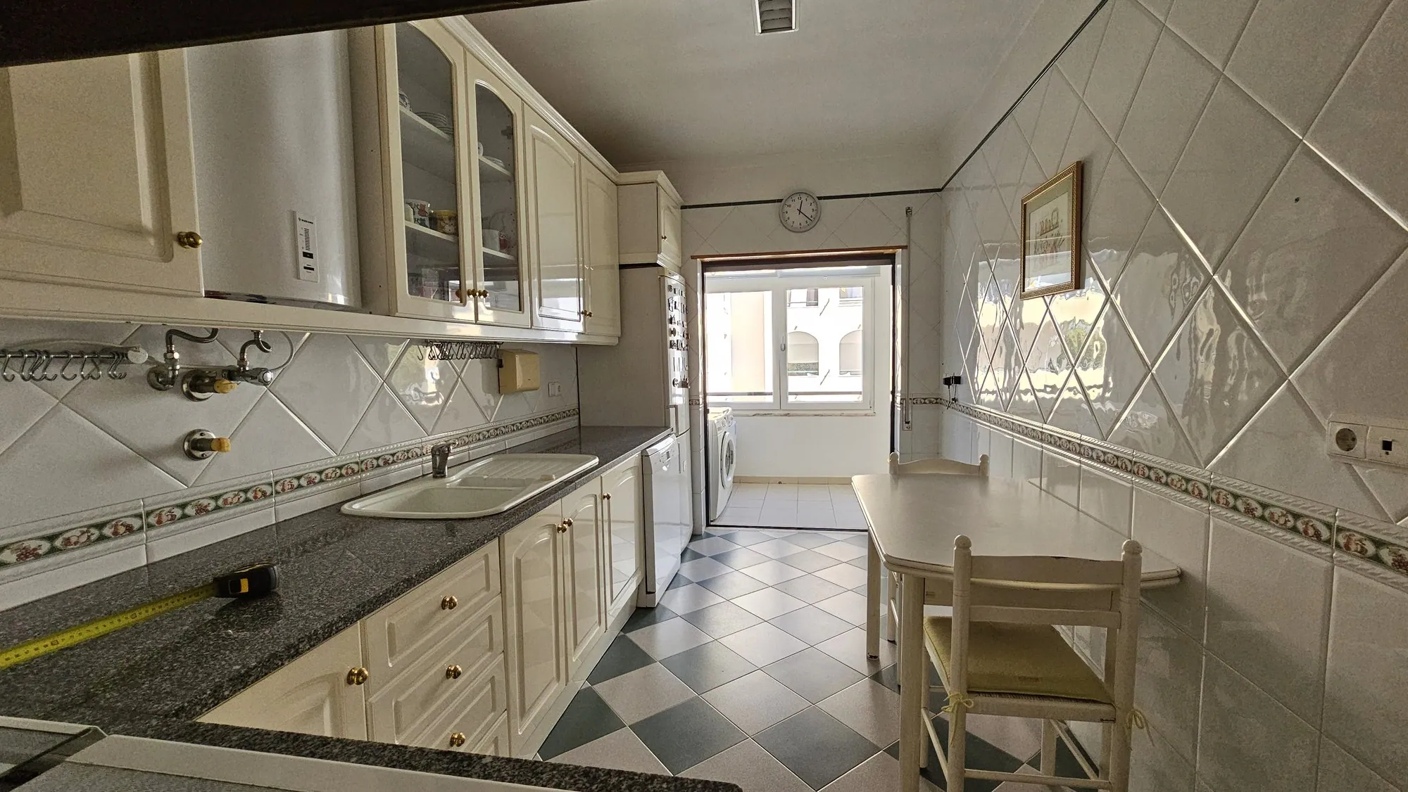 A bancada antes, com armários de frente creme e azulejo branco.