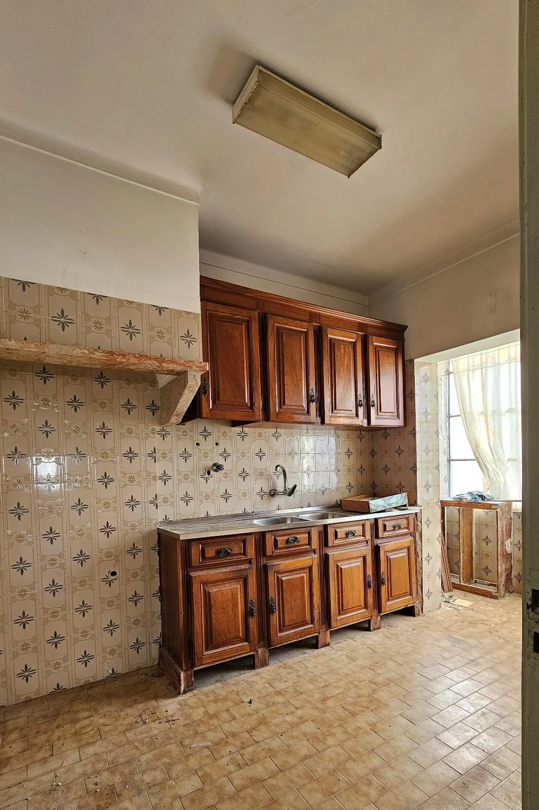 A cozinha antes, com armários de madeira e azulejo decorado.