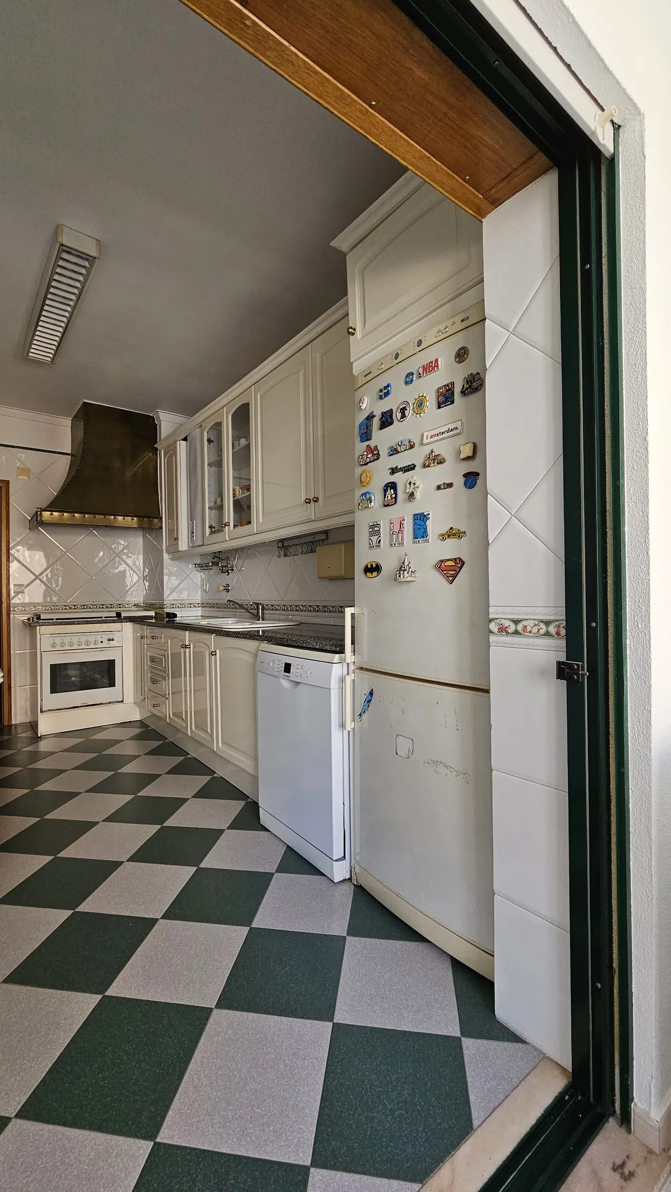 A cozinha antes, com exaustor de cobre e armários creme.