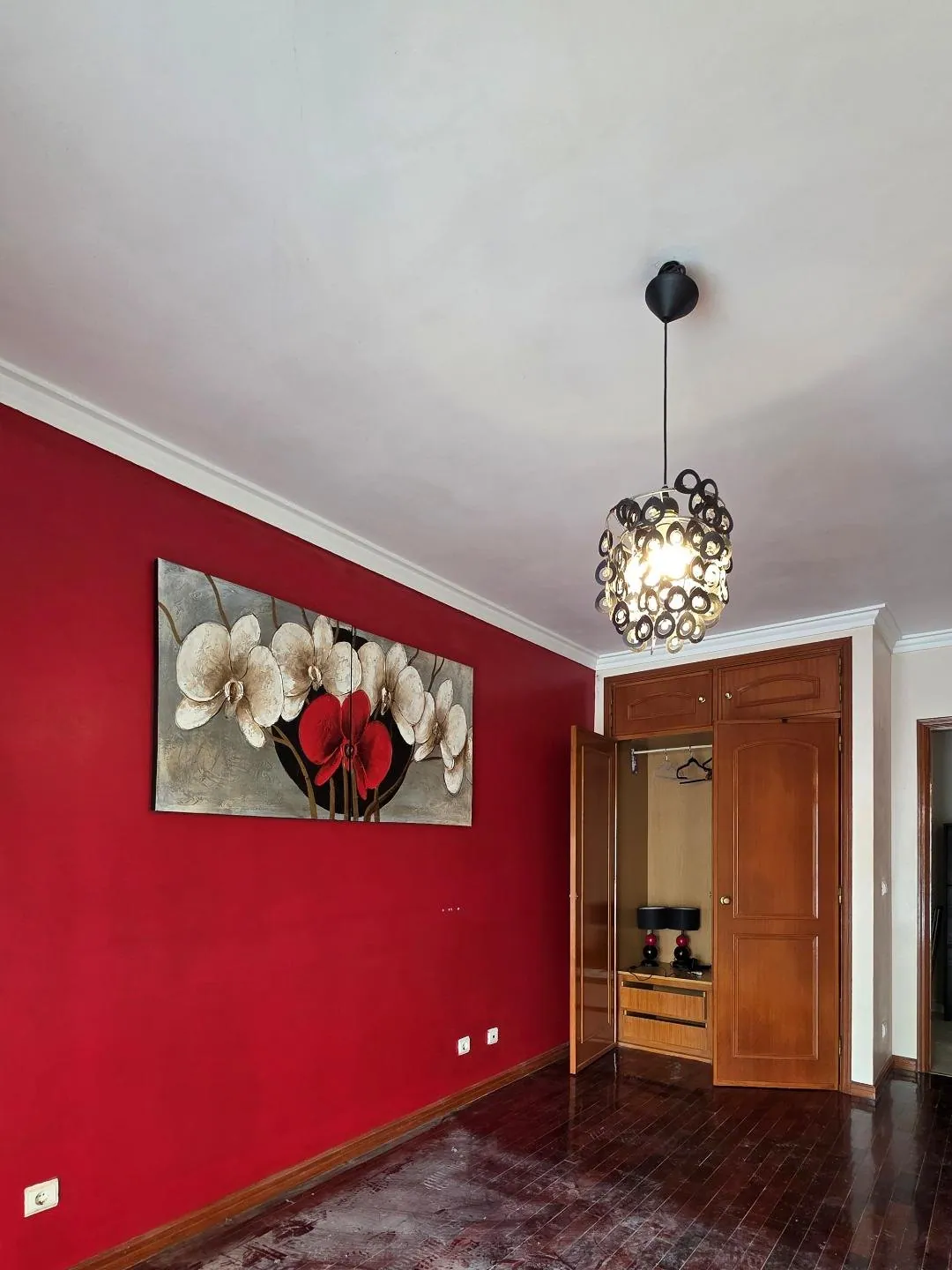 O quarto antes, com parede vermelha e roupeiro de madeira.