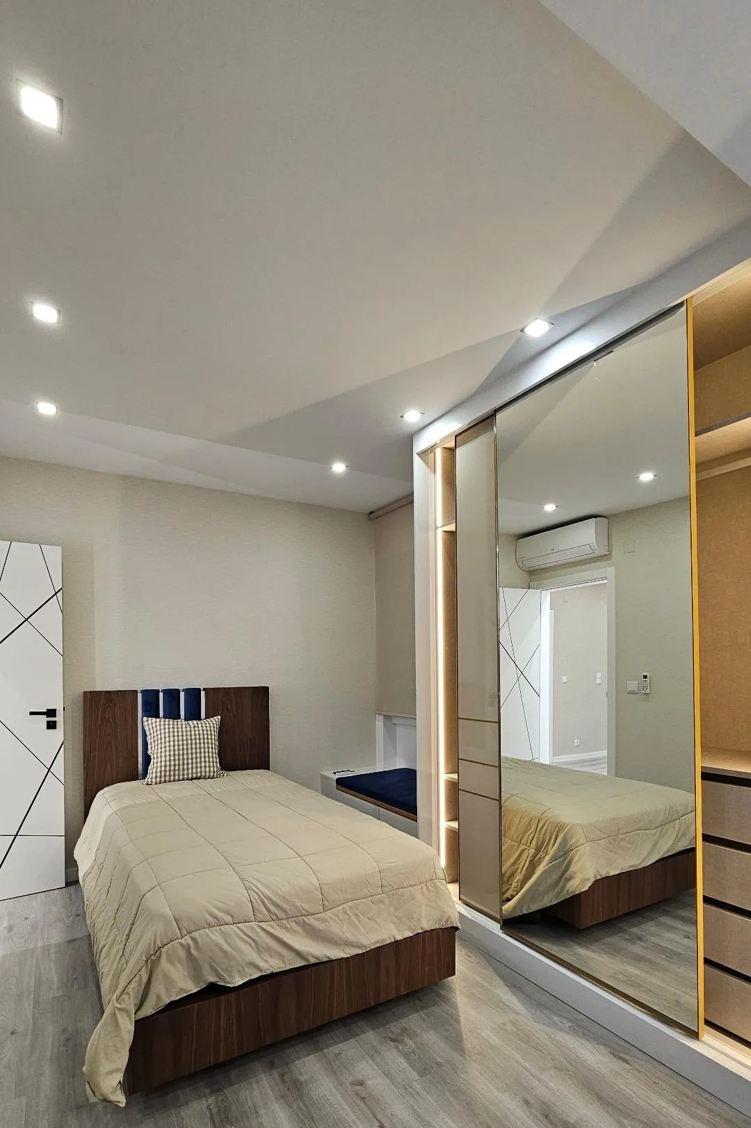 O mesmo quarto depois, com cama de solteiro e roupeiro de espelho.