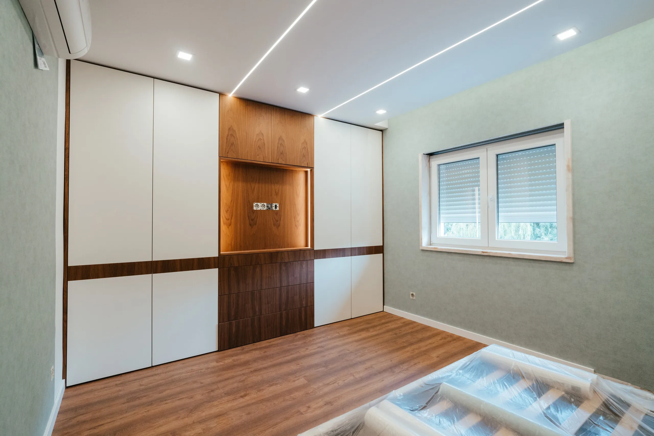 Quarto com roupeiro branco atravessado por uma faixa de nogueira.