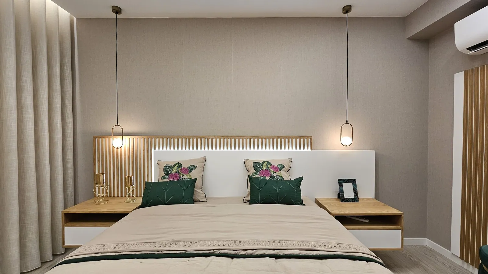 O quarto com cabeceira de ripado de madeira e candeeiros suspensos.