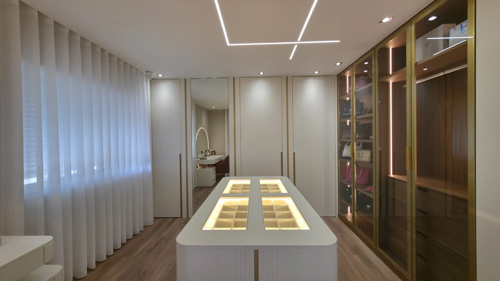 Quarto de vestir com ilha de gavetas iluminada.