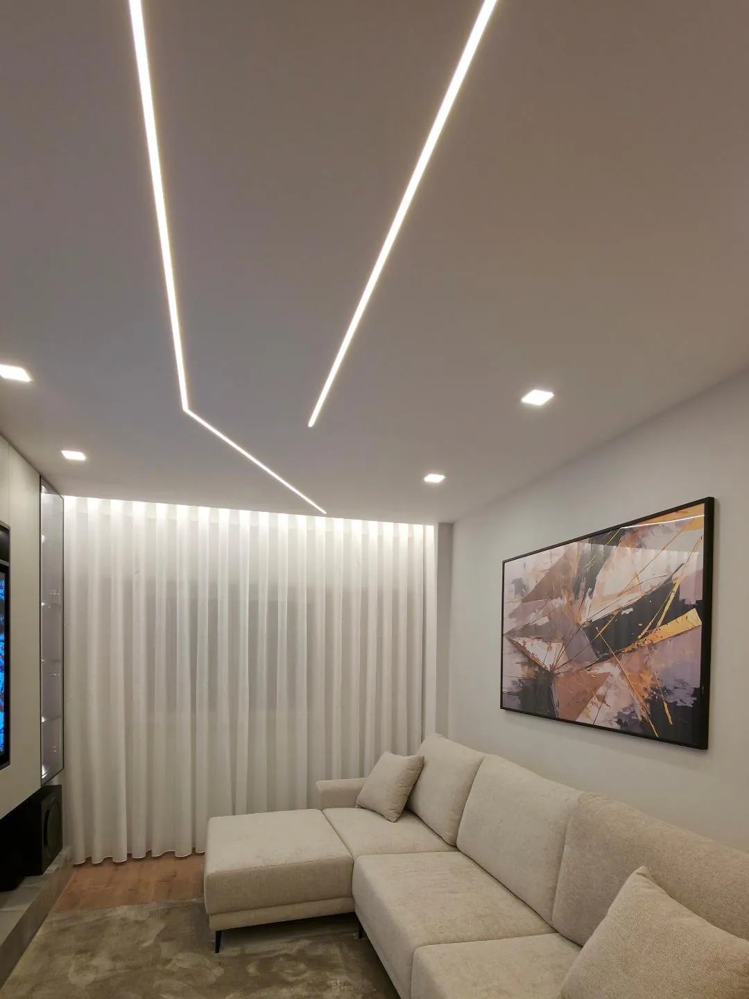 Sala com sofá claro, tapete e cortinados até ao chão.